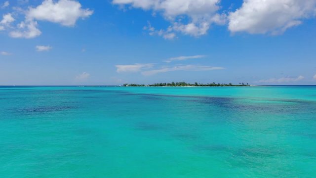 Aerial: Gliding Across Beautiful Tropical Water Towards Deserted Island on a Sunny Day - Nassau, Bahamas