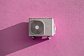 Modern air conditioner compressor on grunge pink wall with isometric shadow, copy space, trendy...