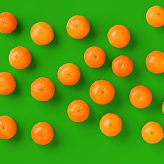 Fruit pattern of fresh orange tangerine or mandarin over green background. Flat lay, top view. Pop art design, creative summer concept. Citrus in minimal style..