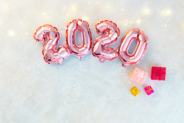 Pink numbers 2020 on a white background. A garland of stars shimmering with colorful lights.