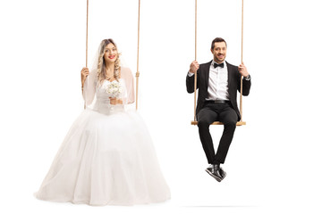 Bride and groom sitting on wooden swings