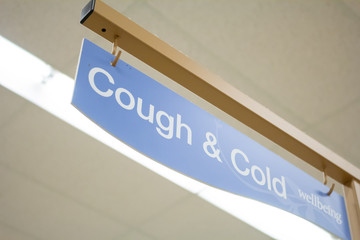 In a grocery store, a view of a sign for products in the Cough and Cold aisle.