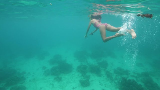Young woman swimming underwater in a sea.