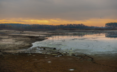 Gloomy morning: yellow sunrise on half-dry lake