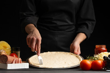 Chef cooks Italian pizza on the background with ingredients.