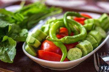 Fresh vegetables - green peppers, tomatoes, cucumbers and greens on the table. Traditional turkish breakfast.
