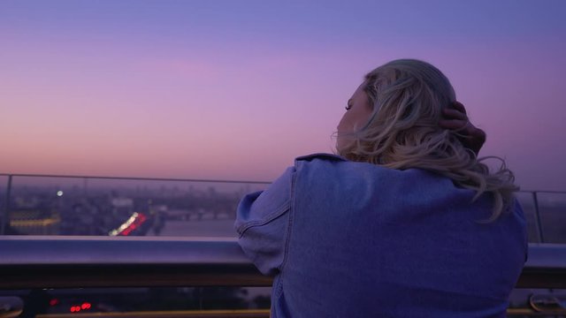 Sad pensive woman standing on windy night bridge alone, relationship problems