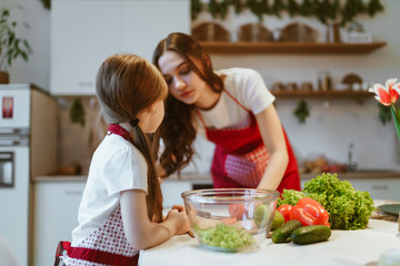 mom and daughter cut vegetables in the kitchen