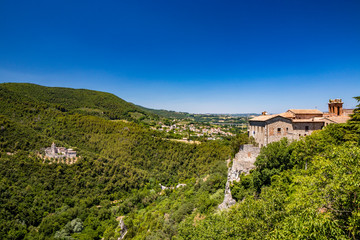 A characteristic glimpse of the ancient medieval village of Narni. Umbria, Terni, Italy. The blue sky on a summer day. The valley below with the green hills. The Benedictine Abbey of San Cassiano.