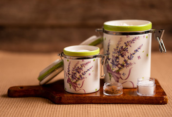 Containers for flour and sugar on a chopping board, brown background