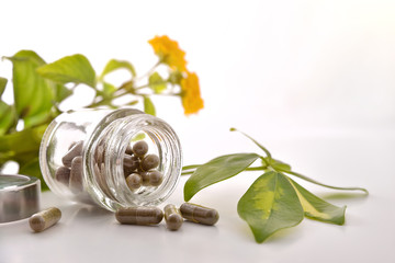 Natural medicine capsules in open glass jar on table front
