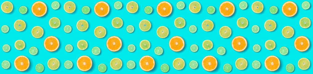 Creative layout made of colorful tropical fruits isolated on blue background. Minimal summer exotic concept. Citrus fruit seamless pattern. Orange, Lime, Lemon slices background. Banner.