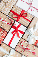 Fototapeta premium New Year composition. Christmas background with red, craft, white wrapped gifts boxes with colorful ribbon and rope, candy canes. Winter holiday pattern. Top view, flat lay, close up. 