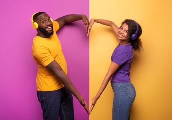 Couple with headset listen to music and make the shape of heart with arms. violet and yellow...