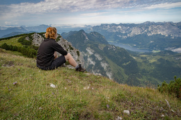 A young woman relaxes with a view of a mountain lake after a busy hike