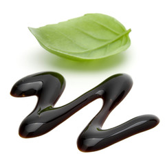 Balsamic vinegar cream and basil leaves isolated on white background. Italian salad dressing, sauce.