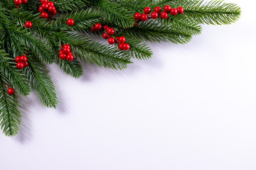 Christmas background with fir branches and holly berries. Copy space.