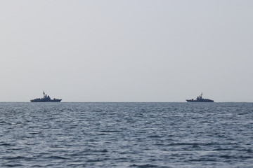 Warships moving in sea toward each other. Two navy ships on the horizon.