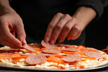 The chef cooks pizza, spreads salami on the background with ingredients. Recipe book, menu, home cooking. Close up macro