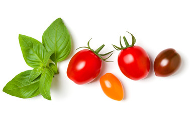 various colorful tomatoes and basil leaves isolated on white background. Top view, flat lay. Creative layout.
