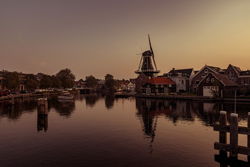 Fototapeta na wymiar Boat anchored on a canal in Amsterdam at sunrise, windmill