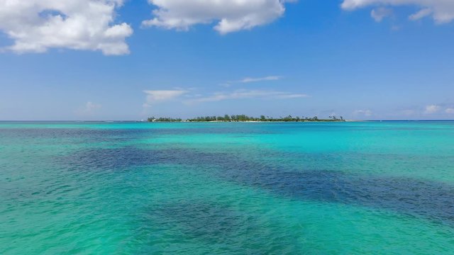 Aerial: Gliding Across Serene Tropical Water Towards Deserted Island on a Sunny Day - Nassau, Bahamas
