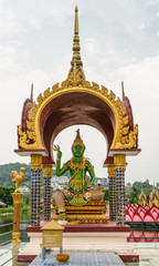 Ko Samui Island, Thailand - March 18, 2019: Wat Laem Suwannaram Chinese Buddhist Temple. Closeup of Lord Vishnu statue, in green Buddha avatar, sitting under golden baldachin. © Klodien