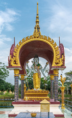Ko Samui Island, Thailand - March 18, 2019: Wat Laem Suwannaram Chinese Buddhist Temple. Closeup of standing white Lord Vishnu statue under golden baldachin. Green foliage and blue cloudscape. © Klodien