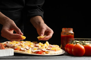 Chef cooks pizza, spreads sliced ​​pineapples, on a background with ingredients. Recipe book, menu, home cooking.