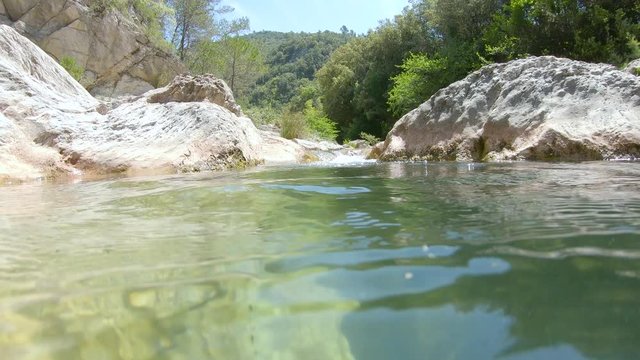 Rocky stream, moving camera over and under water surface, Spain, La Muga river, Catalonia