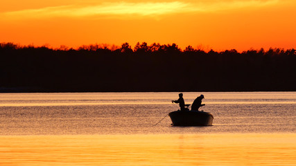 Silhouette of father and son fishing on a beautiful lake at sunset in northern Minnesota.