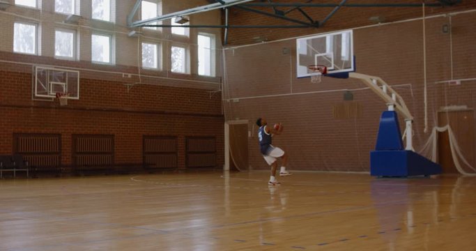 WIDE African American black college male basketball player practicing alley-oops alone on the indoor court. 4K UHD 120 FPS SLOW MOTION RAW Graded footage