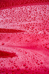 hood of red car, covered in raindrops