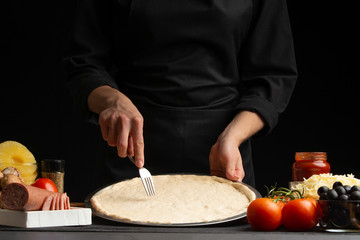 Chef cooks Italian pizza on the background with ingredients.