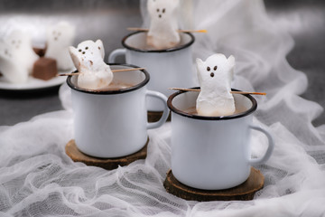 Hot chocolate and marshmallow ghosts served in mugs against a white, spooky background