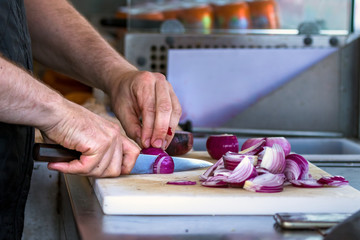 Fototapeta na wymiar Male hand cutting - chopping red onions, sun light, outdoors.