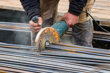 Male hands cutting steel bars with a circular electric grinder, outdoors in Nuuk, Greenland. © Ruben