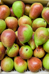 Box with pears top view. Beautiful juicy pears laid out in a box, red-green skin.