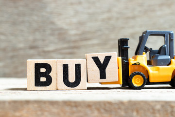 Toy forklift hold letter block y to complete word buy on wood background © bankrx