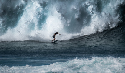 Surfer rides giant wave breaking at the famous Banzai Pipeline surf spot located on the North Shore of Oahu in Hawaii