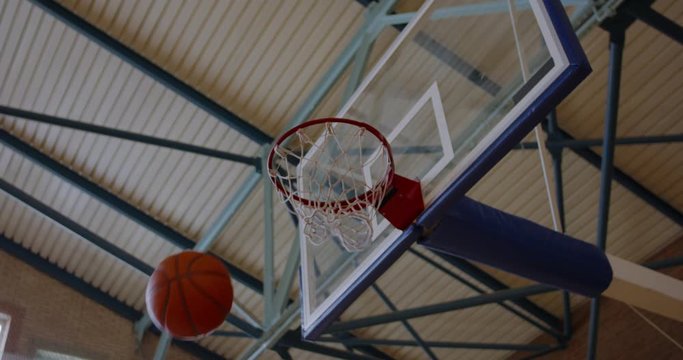 LOW ANGLE African American black college male basketball player practicing dunks alone on the indoor court. 4K UHD 120 FPS SLOW MOTION RAW Graded footage