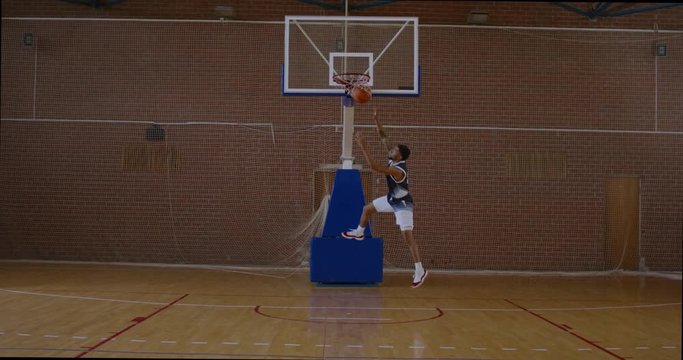 WIDE African American black college male basketball player practicing dunks alone on the indoor court. 4K UHD 120 FPS SLOW MOTION RAW Graded footage