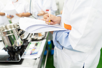 Male students write down recipes , lab technician writing report on results of chemical experiments in notebook