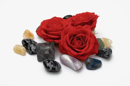 Red roses with smooth pebbles clustered on a white background.