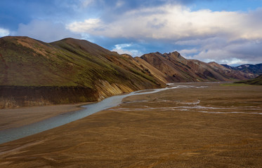 Fototapeta na wymiar Iceland in september 2019. Great Valley Park Landmannalaugar, surrounded by mountains of rhyolite and unmelted snow. In the valley built large camp. The concept of world tours. Aerial drone shot.