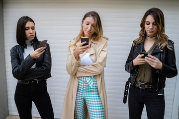 Anti social conduct , three young woman obsessed with smart phones, smart phone addiction concept 