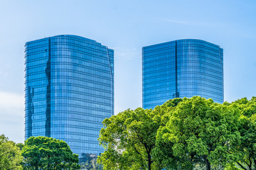 green trees front of modern glass office building.