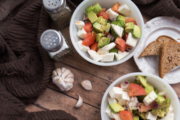 healthy salad from fresh vegetables with avocado, tomatoes and fresh mozzarella cheese served in white bowl