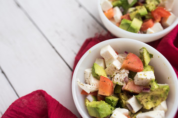 healthy salad from fresh vegetables with avocado, tomatoes and fresh mozzarella cheese served in white bowl