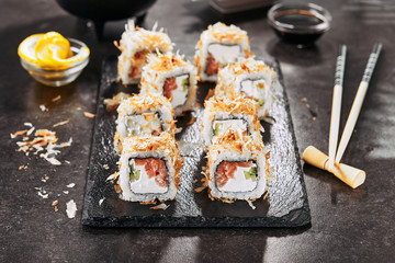 Macro shot of uramaki sushi rolls with cream cheese, salmon, tuna shavings or dried bonito, cucumber, nori. Portion of fresh katsuobushi roll in Japanese restaurant closeup
